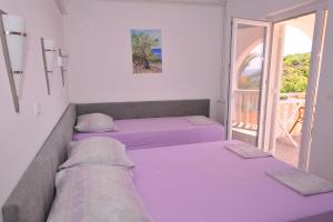 2 łóżka w pokoju z fioletową pościelą w obiekcie Family friendly apartments with a swimming pool Potocnica, Pag - 3075 w Novalji