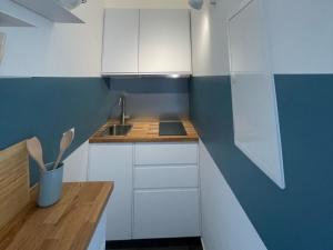 a small kitchen with white cabinets and a blue wall at Illas Koje - Fehmarn in Westerbergen