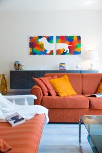 a living room with a orange couch and colorful paintings at San Giovanni in San Gimignano