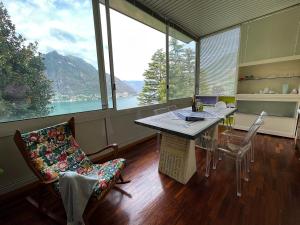 Habitación con mesa, sillas y ventana grande. en Lake Como Villa Ines Junior Apartment, en Faggeto Lario 