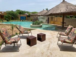 un grupo de sillas sentadas junto a una piscina en Villa avec piscine à Ndangane, en Ndangane