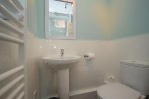 a bathroom with a sink and a toilet and a mirror at Otter Apartment in Tobermory