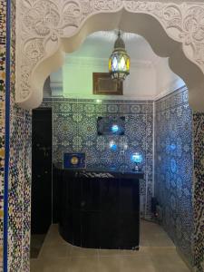 Zimmer mit einer blau gefliesten Wand und einem Kronleuchter in der Unterkunft Dar Dikrayat in Marrakesch