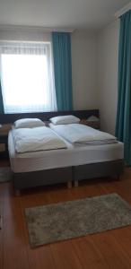 ein Bett in einem Schlafzimmer mit einem Fenster und einem Teppich in der Unterkunft Belvárosi Apartman Lux in Hajdúszoboszló