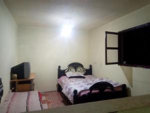ein kleines Schlafzimmer mit einem Bett und einem TV in der Unterkunft Atlas TAHANAOUT in Tahannaout