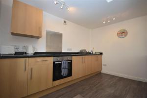 cocina con armarios de madera y lavavajillas negro en Puffin Apartment, en Tobermory