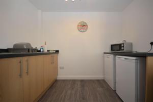 a kitchen with wooden cabinets and a clock on the wall at Puffin Apartment in Tobermory