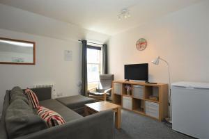 a living room with a couch and a flat screen tv at Dolphin Apartment in Tobermory