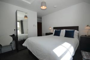 a bedroom with a large white bed with blue pillows at Dolphin Apartment in Tobermory