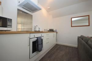 uma cozinha com fogão forno ao lado de um sofá em Dolphin Apartment em Tobermory