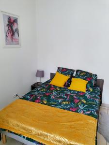 1 dormitorio con 1 cama con almohadas amarillas en Entre arènes et maison carrée P1, en Nimes