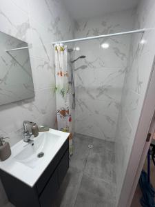 a bathroom with a shower and a white sink at סטודיו חדש ויפה עם נוף לים in Netanya