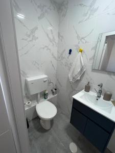 Baño blanco con aseo y lavamanos en סטודיו חדש ויפה עם נוף לים, en Netanya