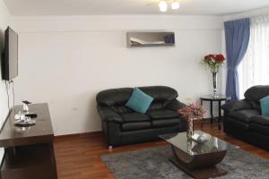 a living room with a black couch and a table at Buen Retiro Apart Hotel in Santa Cruz de la Sierra
