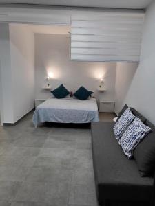a bedroom with a bed with blue pillows and a couch at Marga STUDIO H10 in Arona +20 photos