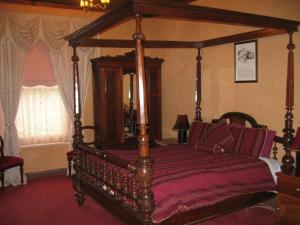 een slaapkamer met een houten hemelbed met rode lakens bij Mintaro Hideaway in Mintaro