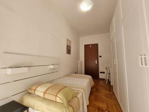 two beds in a room with white walls and wooden floors at Apt by Trieste University in Trieste