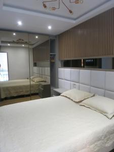 um quarto com uma grande cama branca e um espelho em Apartamento luxuoso com infra completa próximo a Praia da Barra da Tijuca no Rio de Janeiro