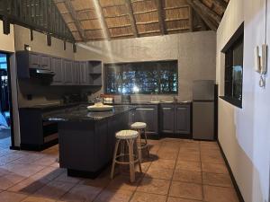 a kitchen with a black island and two bar stools at Acoustic Guest House in Pretoria