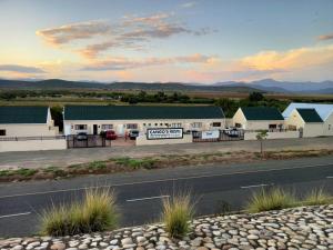 eine Reihe von Gebäuden mit einer Straße vor ihnen in der Unterkunft Cango's Rest in Oudtshoorn