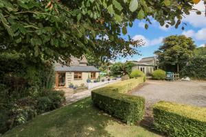 a house with hedges in front of a driveway at Silverwell Forge in Chacewater