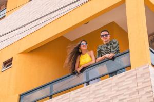 un homme et une femme regardant par une fenêtre dans l'établissement Pousada Praia Dos Encantos, à Japaratinga