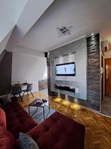 a living room with a couch and a tv on a wall at Apartman Filip Novi Sad in Novi Sad