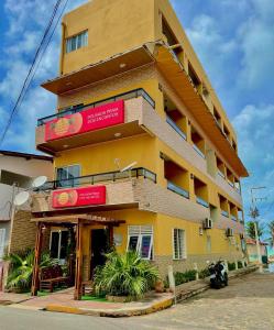 um edifício amarelo com sinais vermelhos em Pousada Praia Dos Encantos em Japaratinga