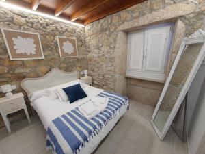 1 dormitorio con cama y pared de piedra en Casa María, en Muxía
