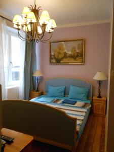 a bedroom with a bed with blue sheets and a chandelier at Orient Express Guest House in Sofia