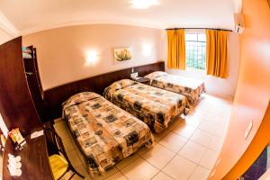 a hotel room with two beds and a window at Vila Verde Hotel in Toledo