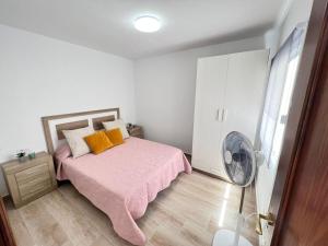 een slaapkamer met een roze bed en een ventilator bij ÁTICO VISTA TEIDE in Arona