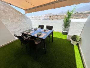 een tafel en stoelen op een balkon met groen gras bij ÁTICO VISTA TEIDE in Arona