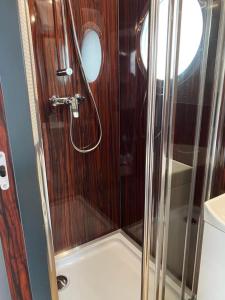 a shower with a glass door on a boat at Couston Lakes Resorts in Bathgate