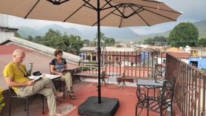 a man and woman sitting on a balcony under an umbrella at La Capitanía in Antigua Guatemala