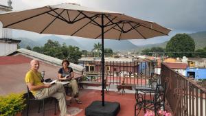 a man and woman sitting on a balcony under an umbrella at La Capitanía in Antigua Guatemala