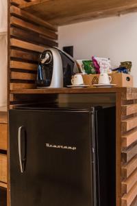 um frigorífico preto numa cozinha com uma prateleira de madeira em Triângulo Noronha em Fernando de Noronha