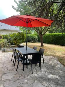 a black table and chairs with a red umbrella at Un Mendi in Argelès-Gazost