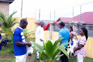 un gruppo di persone che si aggirano intorno a una pianta di Justa Hotel Annex a Accra
