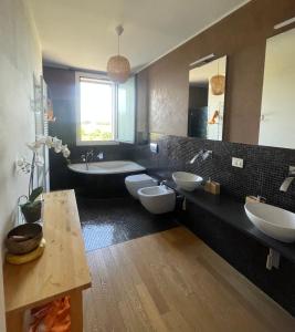 ein Badezimmer mit zwei Waschbecken, einer Badewanne und zwei WCs in der Unterkunft MalaMù BnB Eventi in Rigosa