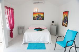 a white bedroom with a bed and two blue chairs at Cosmopolitan Guesthouse in Hopkins