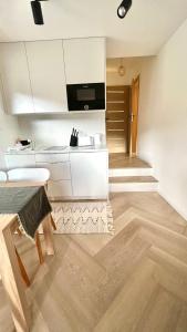 a kitchen with white cabinets and a wooden floor at Apartament 21 (1) in Szczyrk