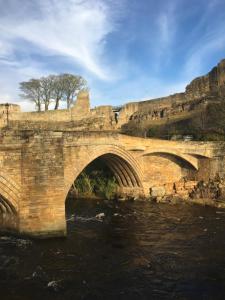 a stone bridge over a river with a mountain in the background at Grade II listed house with river and castle views - Barnard Castle in Barnard Castle