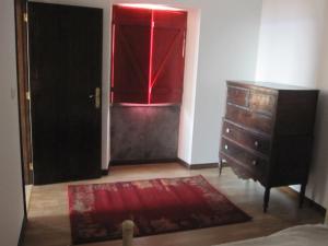 Cette chambre comprend une commode et une fenêtre rouge. dans l'établissement Casa do Jardim de Lava, à Arcos