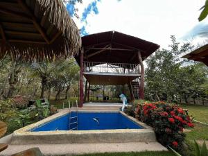 a swimming pool in a garden with a pavilion at Casa vacacional Brisas del Mar in San Juanillo