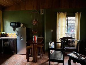 a kitchen with green walls and a table and a refrigerator at Casa vacacional Brisas del Mar in San Juanillo