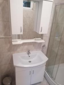 a bathroom with a white sink and a shower at Sphinx Apartment in Visoko