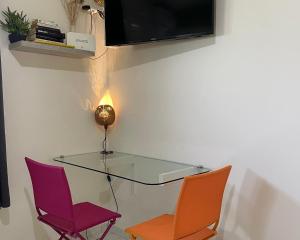 un tavolo in vetro con due sedie e una TV a parete di Colibri de la Pointe a Le Robert