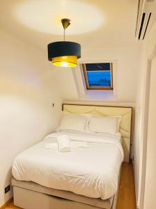 een kleine slaapkamer met een wit bed en een raam bij APPARTEMENT AVEC VUE SUR LA TOUR EIIFEL in Issy-les-Moulineaux