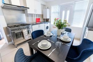 a kitchen with a dining table and chairs and a kitchen with a stove at Beautiful 4 bedroom house with free parking Luton in Luton